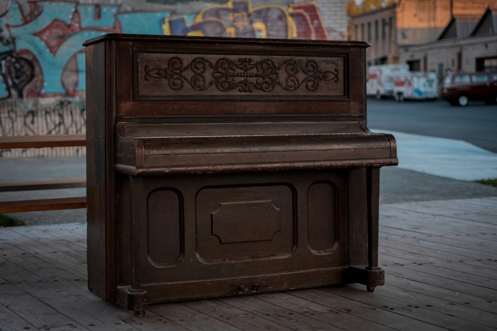 An old piano sitting on the side of the road
